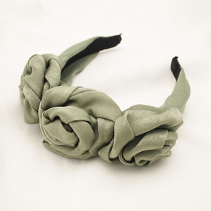 Detailed top view of bean green satin headband with three handmade fabric roses