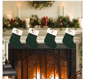 Détail de quatre chaussettes de Noël en tricot vert avec lettres brodées rouges K C Y P