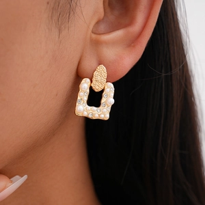 Detailed view of vintage gold U-shaped earrings with pearls and crystals on ear