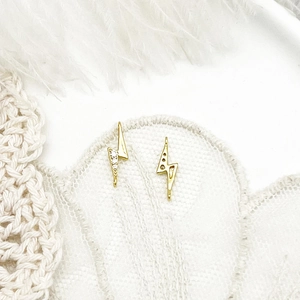 Detail of lightning bolt charms in 18K gold plating with micro-pave crystals on lace fabric