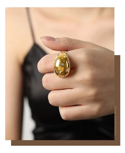 Detail of gold teardrop ring with colorful inset gemstones worn by a stylish model