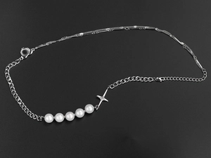Detailed shot of silver cross pendant with reflective pearls on a combined chain necklace