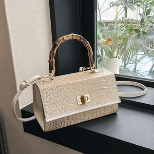 Detailed close-up of bamboo handle and cream faux crocodile leather texture on the handbag