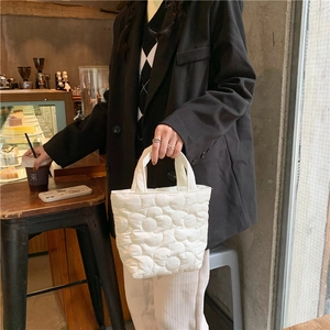 Detailed shot of white quilted handbag with 3D floral texture in a cafe setting