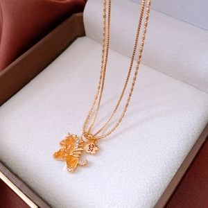 Détail du pendentif licorne plaqué or 18 carats avec pierres orange et breloque fleurie