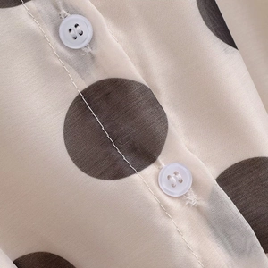 Détail du tissu à pois et du bouton blanc sur une robe de style français élégante