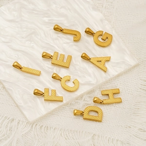 Golden stainless steel alphabet pendants with textured finish on marble surface