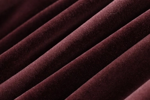 Close-up of deep wine red velvet fabric showing soft texture and elegant draping folds