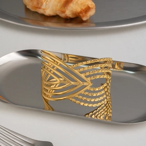 Dettaglio del bracciale rigido dorato a forma di V su un vassoio d'argento lucido