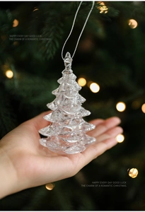 Close-up of a clear acrylic Christmas tree ornament with glitter snow and silver string