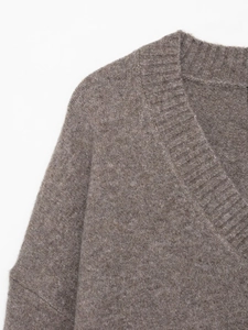 Detailed close-up of V-neckline on soft brown knit sweater with ribbed texture and fine wool