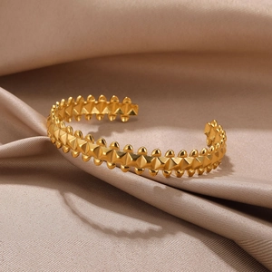 Detailed shot of golden pyramid studs and bead texture on a geometric open bangle