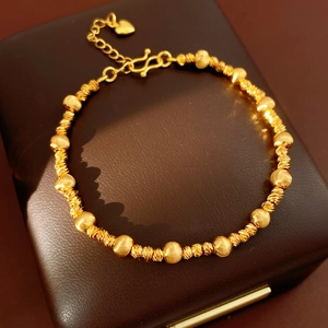 Macro view of 24k gold-plated gourd bracelet with sandblast beads and heart charm detail