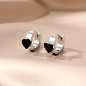 Macro shot of silver stainless steel hoop earrings with black enamel heart details on satin
