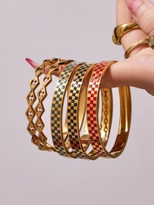 Close-up of gold stainless steel bangle set with enamel checkerboard patterns and crystals