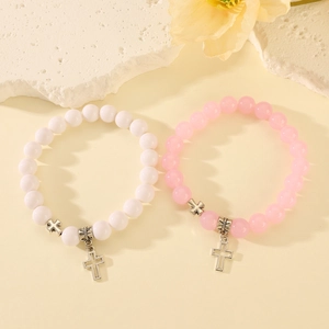 Detalle de pulseras de la amistad con cuentas y dijes de cruz plateados en blanco y rosa