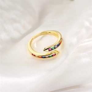Détail macro d'une bague serpent dorée avec zircons colorés sur de la soie blanche