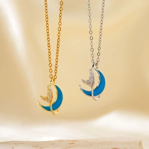 Elegant gold and silver whale moon necklaces with blue cubic zirconia on textured stone