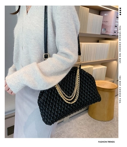 Detail of black woven shoulder bag with triple-layer gold chain straps and leather finish