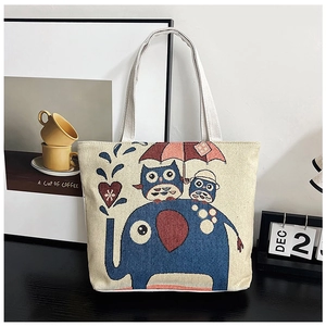 Detail of canvas tote bag featuring elephant, owls, and a red umbrella embroidery