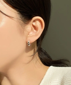 Close-up of small silver 925 hoop earrings with star relief pattern worn by a model
