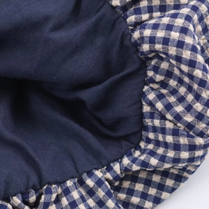 Détail de la doublure bleu marine et du tissu à carreaux avec poignets plissés