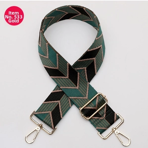 Close-up of geometric woven shoulder strap with gold-tone swivel hooks and adjustable buckle