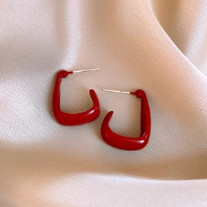 Detail of elegant red U-shaped hoop earrings on champagne silk background