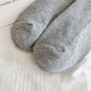 Macro view of light grey ribbed knit socks with detailed cotton texture and seamless toe