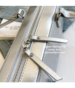 Detail of silver metallic leather handbag featuring double zipper closure and leather tabs