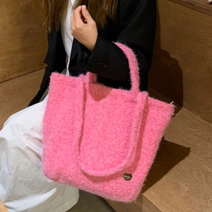 Pink plush faux fur tote bag with heart metal logo shown in a fashion lifestyle scene