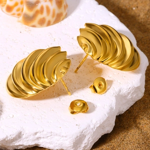 Golden seashell stud earrings with realistic textures on white rock and sand
