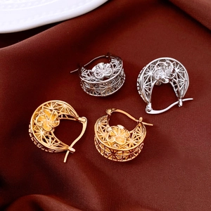 Detailed close-up of hollow flower earrings in gold and silver finish on velvet