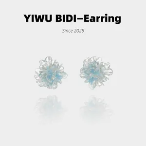 Detailed macro shot of blue flower earrings with gold glitter and silver needles
