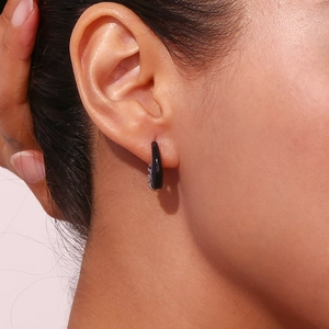 Close-up of black teardrop enamel earring on model ear with polished silver setting