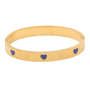 Detailed close-up of golden vintage heart bangle with blue enamel and floral engraving