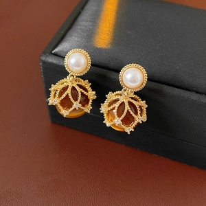 Macro detail of vintage gold starburst earrings with amber stone and pearl on leather