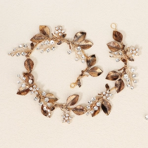 Close-up of bridal headpiece with golden leaves and sparkling rhinestones on beige background
