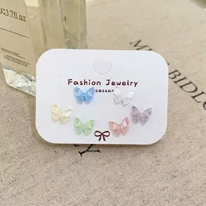 Detailed view of six pairs of butterfly stud earrings in various macaron colors on display card