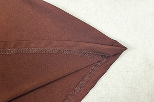 Detailed view of dark brown dress fabric with professional stitching and hem craftsmanship