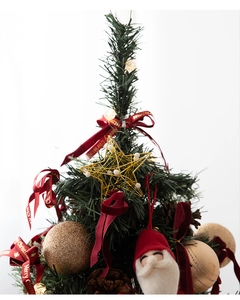 Close-up of small Christmas tree top with gold star, pine cones and Santa ornaments