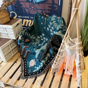 Detailed texture of bohemian woven camping blanket with teal sea life patterns and fringes