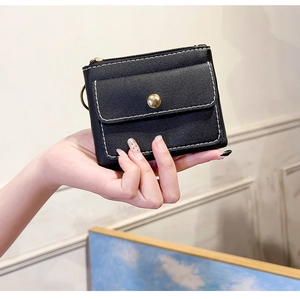 Detail of a black PU leather coin purse featuring contrast white stitching and gold snap button