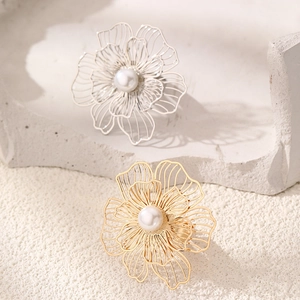 Detailed view of hollow flower rings in gold and silver with pearls on rock textures