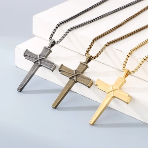 Détail de pendentifs croix clou en or, argent et bronze avec texture de nœud et chaînes