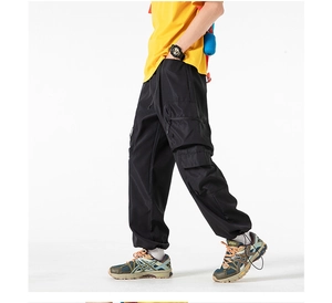 Dettaglio dei pantaloni cargo neri con sistema multitasche e polsini delle caviglie
