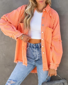 Detailaufnahme der orangefarbenen Jeansjacke mit Distressed-Fransen und Metallknöpfen