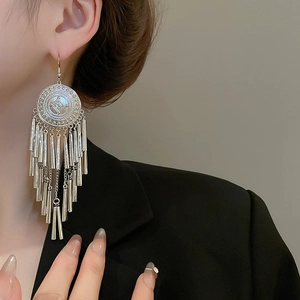 Detailed close-up of a silver long tassel earring on model in retro ethnic style