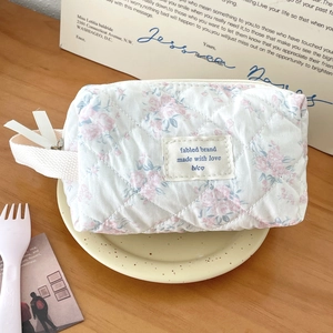Detailed view of quilted cotton makeup bag with floral print and white brand label