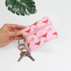 Mini canvas coin purse with pink fox print, top zipper, and metal keychain in hand